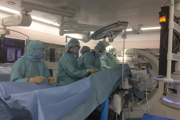 Surgeons perform a procedure, reflecting how emicizumab's efficacy allowed many young hemophilia patients to have permanent venous catheters surgically removed.