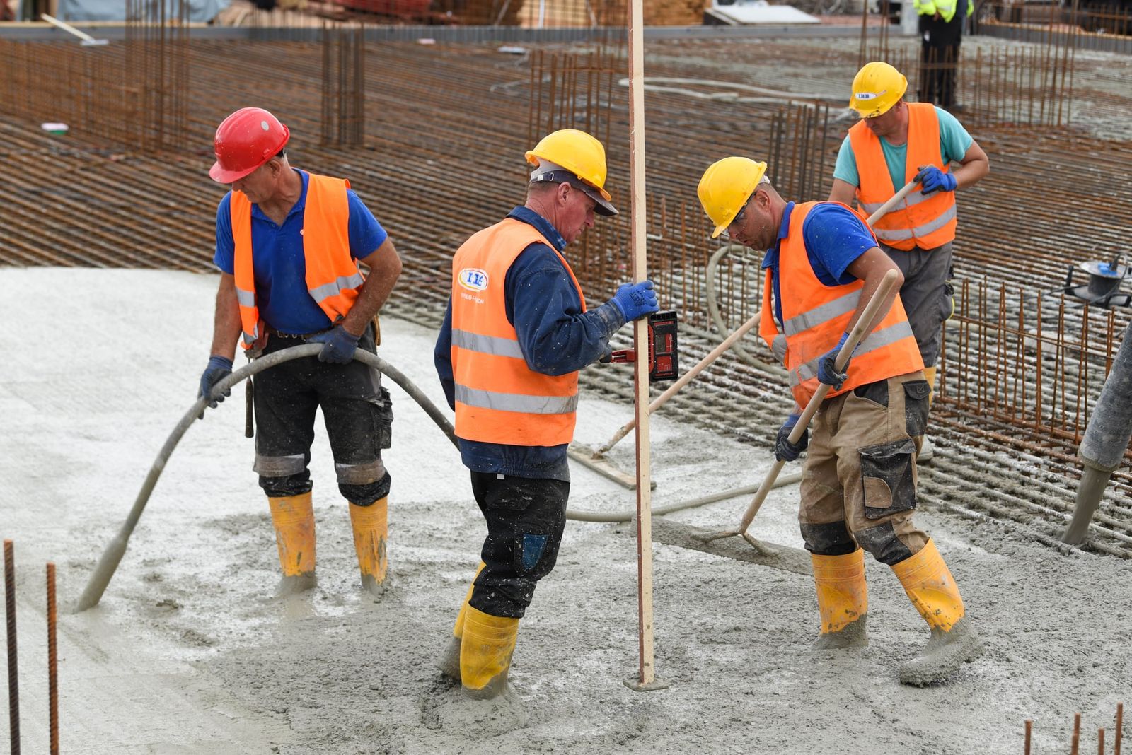 Construction crews, like these workers pouring concrete, face significant risks from rising heat due to their continuous exertion in open weather.