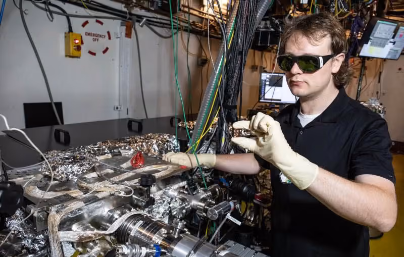A researcher handles a semiconductor sample at the specialized SLAC facility where high-energy electrons revealed hidden speed in radiation detectors.