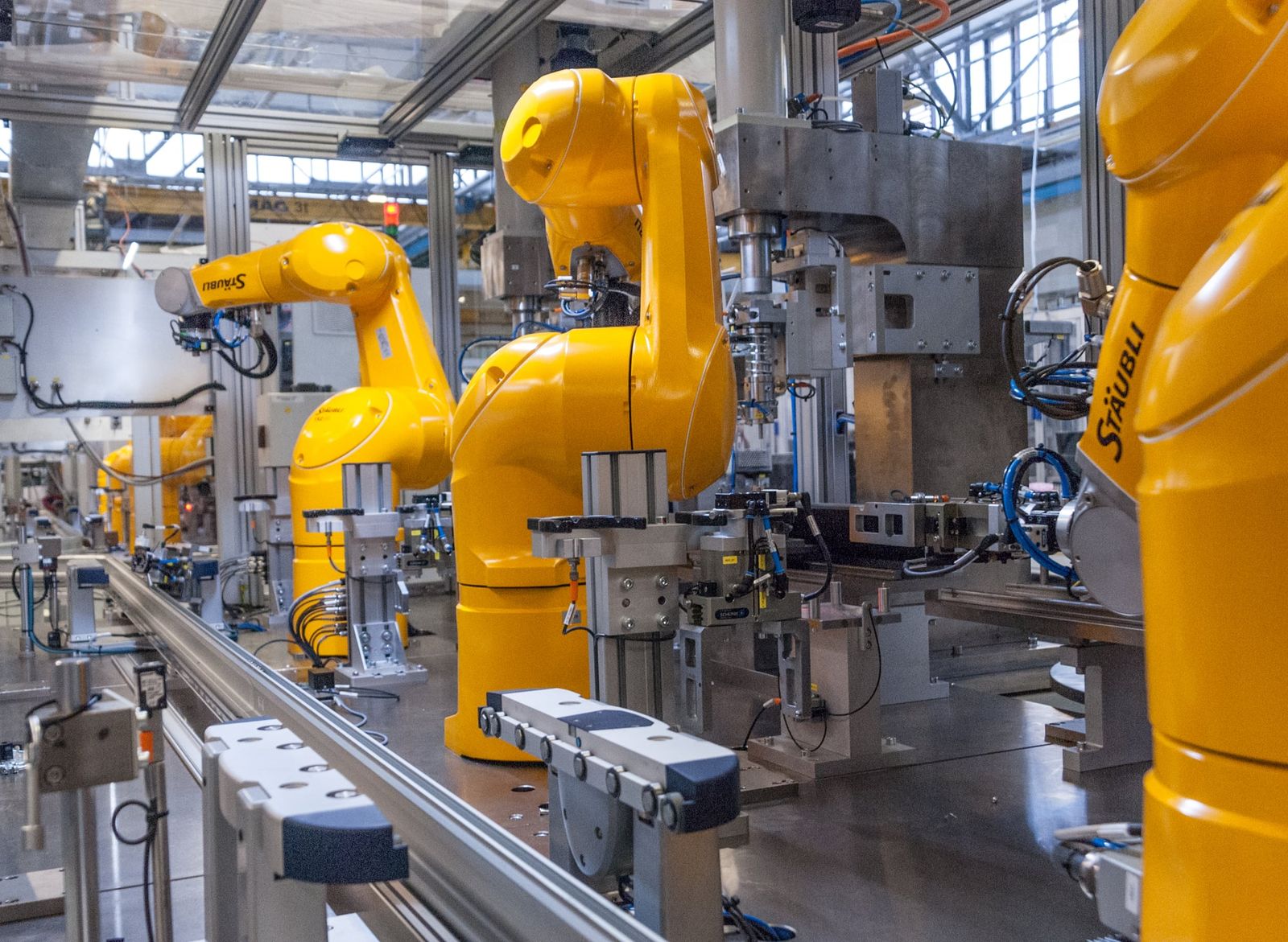 Industrial robots like these represent the physical hardware in manufacturing, which the article notes is distinct from their cognitive control models.